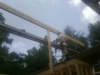 Carpenter setting a ridge beam over a new addition frame — Ice Dam Removal by Roofing Brothers in Newport
