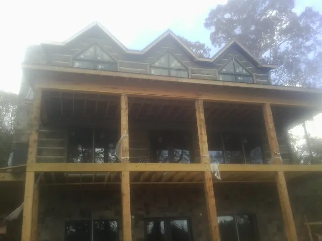 Dormers and porch framing on a large log home under construction — Roof Coating work by our crew in Newport