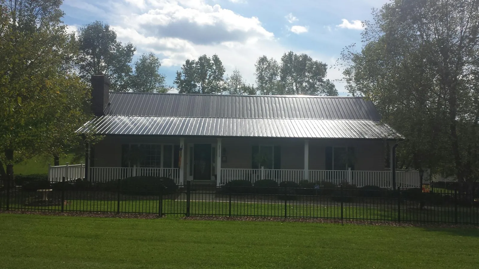 Gray metal roof on a brick ranch with a full width front porch — Gutter Guard Installation work by our crew in Newport
